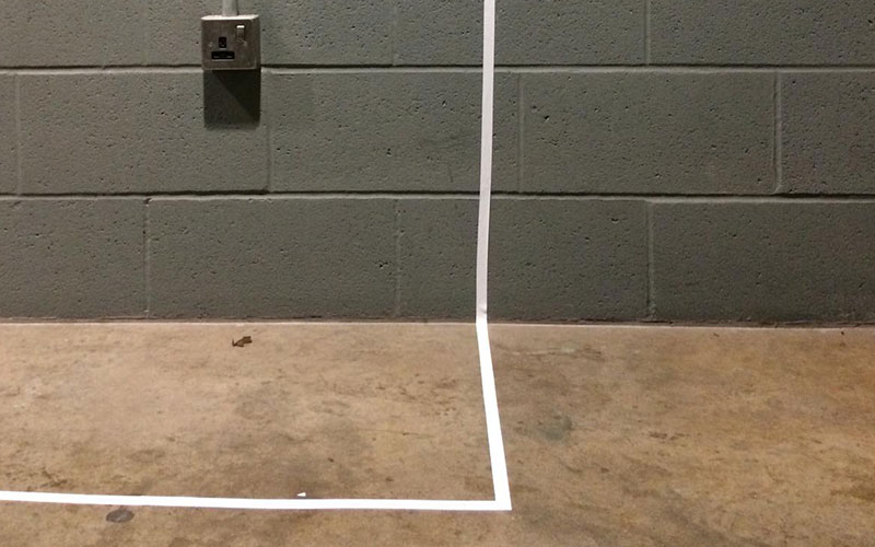 a taped white line from the floor to a wall